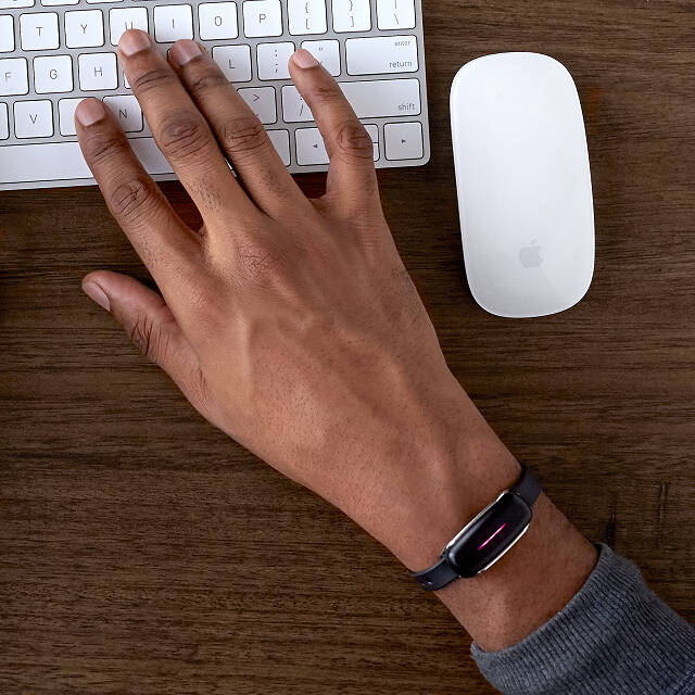 man wearing a bond touch bracelet while working on the computer