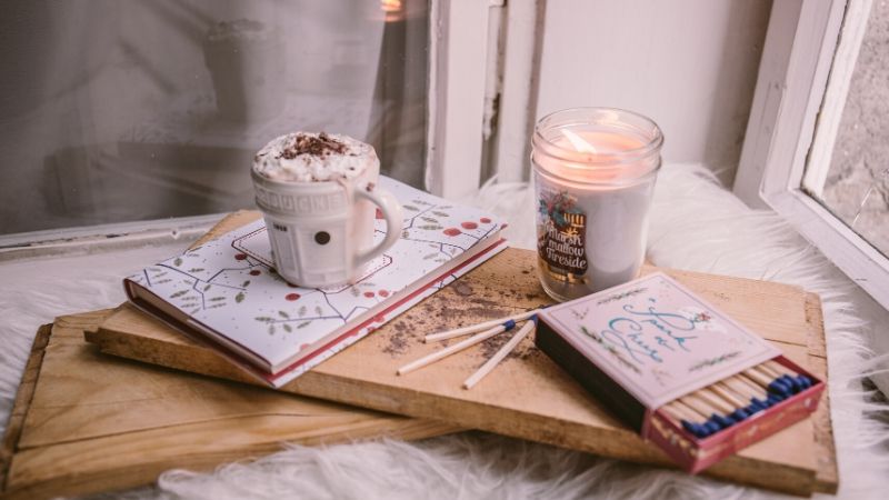 a lit candle and hot chocolate from from a winter themed care package