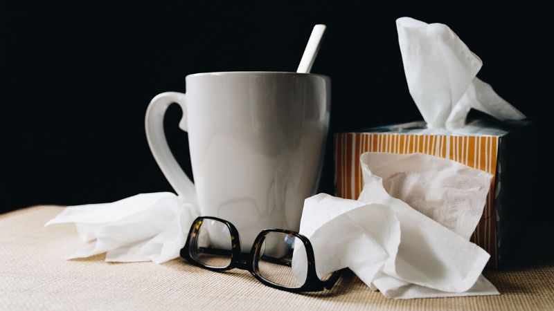 une boisson chaude et des mouchoirs en papier provenant d'un paquet de soins pour malades