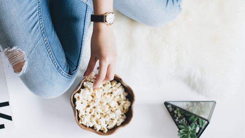 girl eating popcorn she received from a cinema themed care package