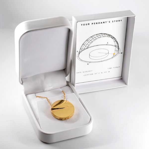 collier pendentif héliodon en or avec coordonnées gravées sur le côté dans une boîte blanche